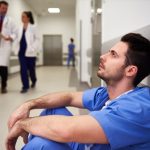 doctor sitting on the floor in a hospital experiencing compassion fatigue
